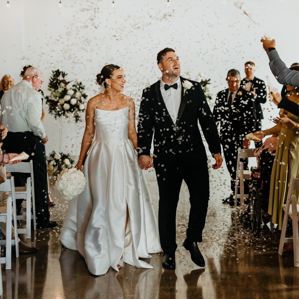 Bride and groom walking back down the aisle with guests throwing confetti over them